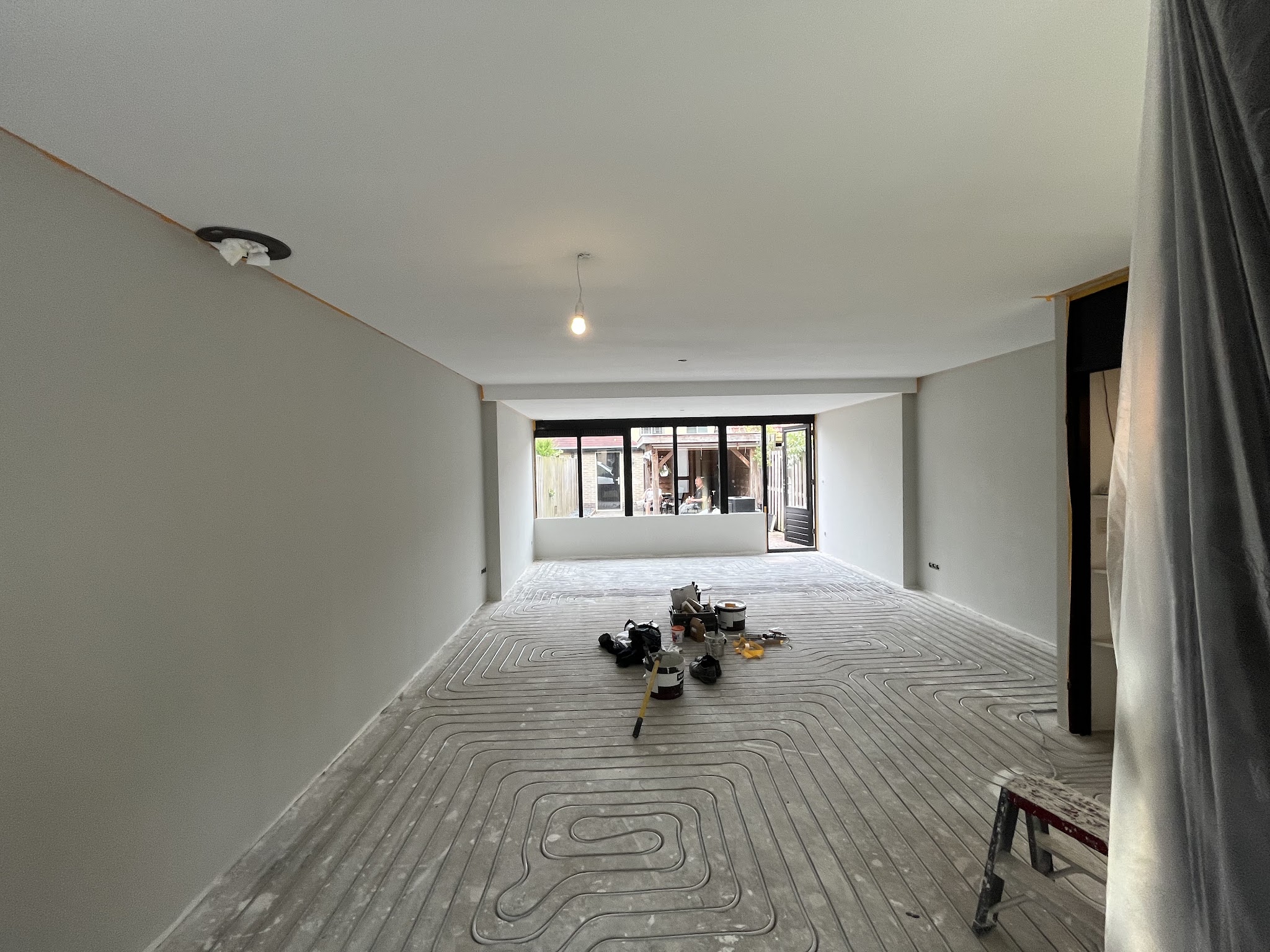 Lange doorzonkamer met gestucte wanden en plafond, vloerverwarming nog zichtbaar