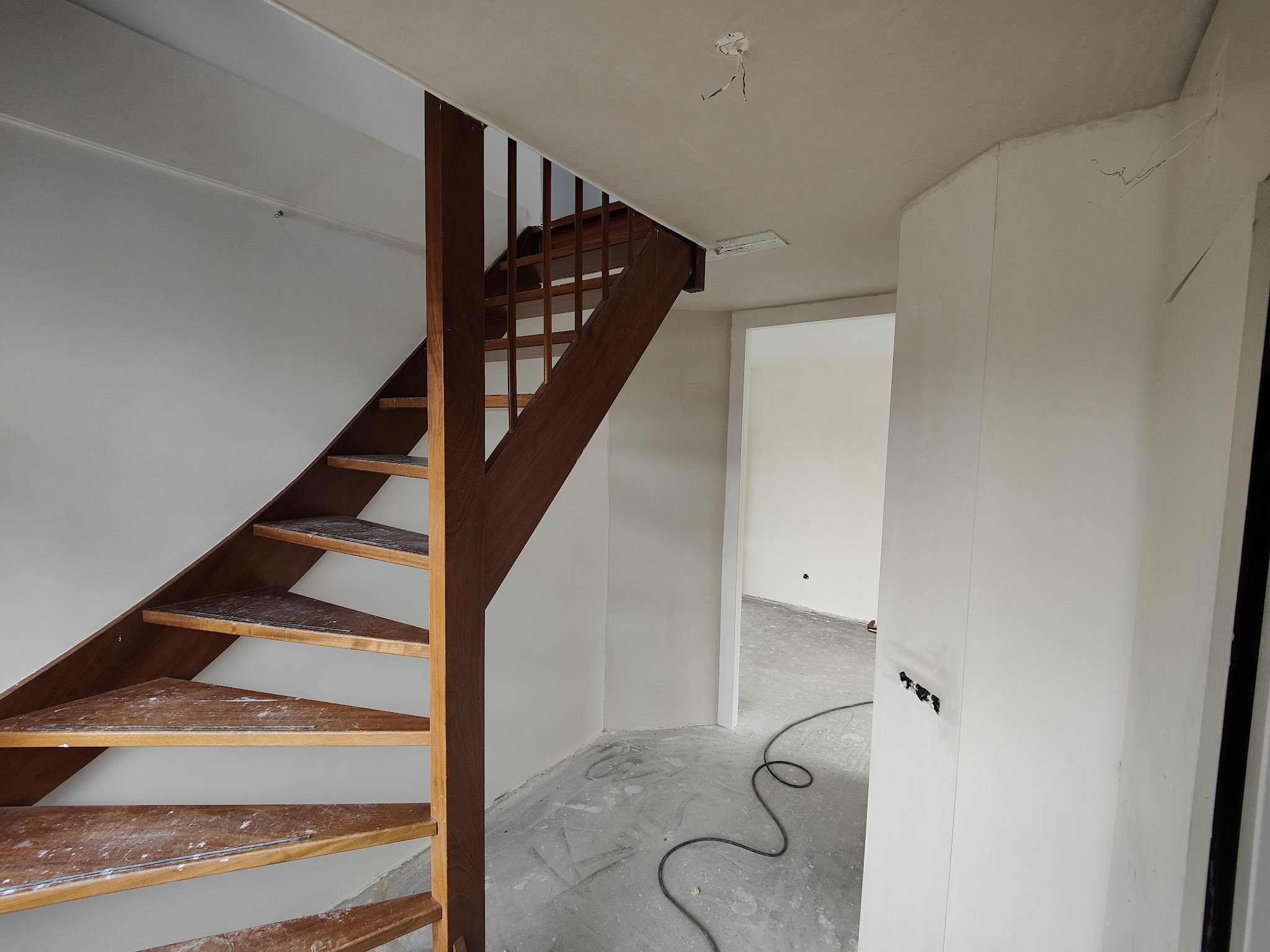 Hal met houten trap en vers gestucte wanden