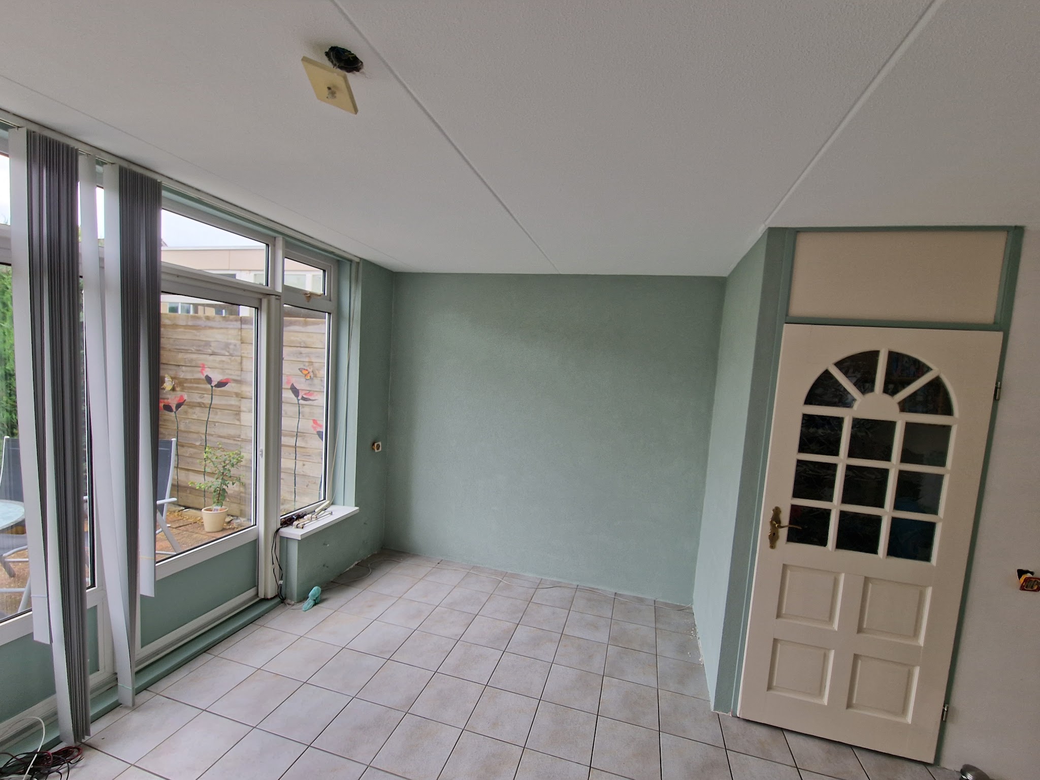 Serre met mintgroene wand en witte deur met boogvenster